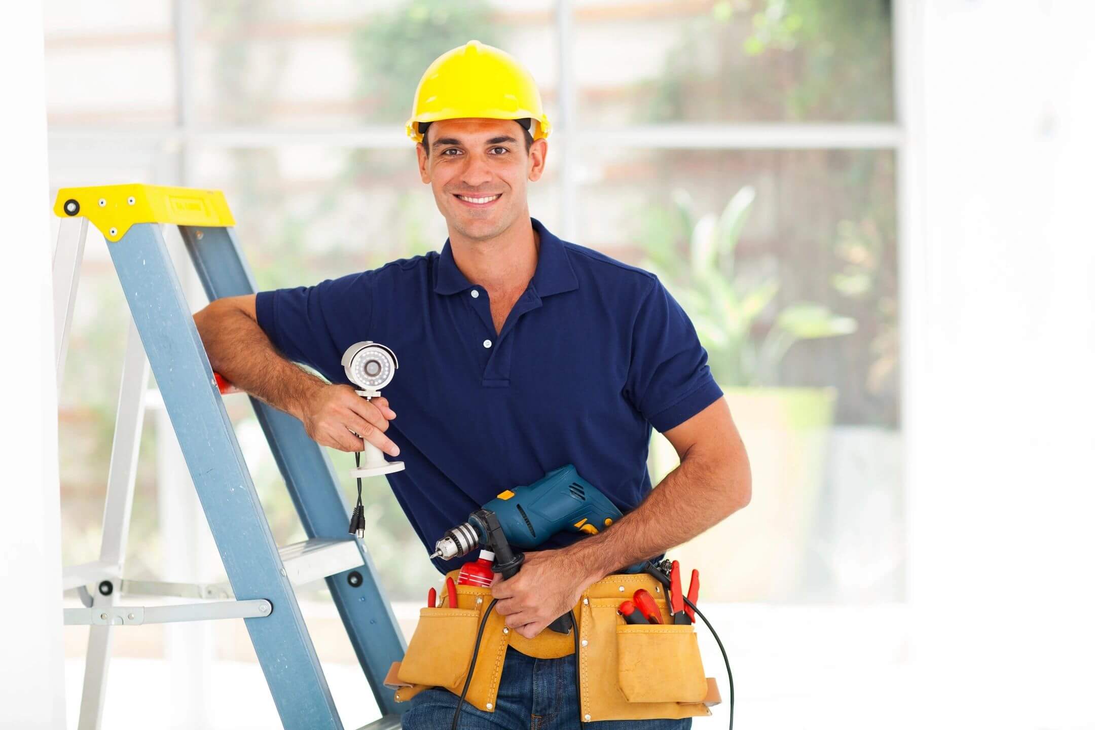 Smiling worker with tools and ladder indoors.